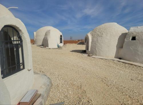 a group of white domed buildings in the desert at Tootya camp in Al Mathlūthah