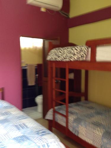 a bedroom with two bunk beds and a bathroom at Hostal Surf Olón in Olón