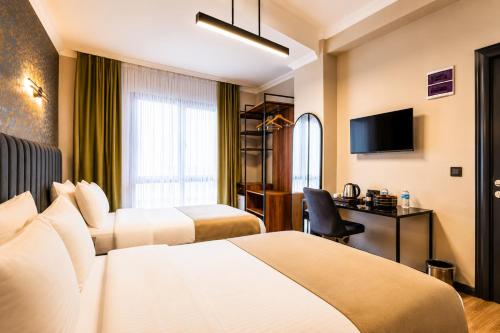 a hotel room with two beds and a desk at Nora Airport Hotel in Arnavutköy