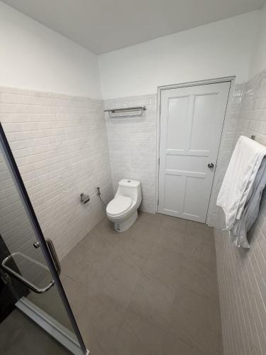 a white bathroom with a toilet and a door at Blue Privacy Resort in Nathon Bay
