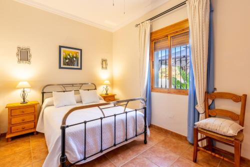a bedroom with a bed and a window and a chair at Casa Mari in Almogía
