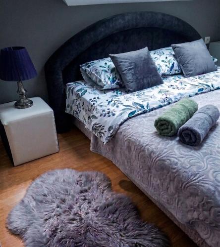 a bedroom with a bed with pillows and a rug at Apartmani Lazaro in Višegrad