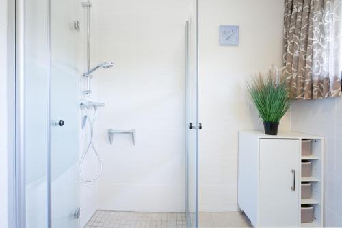 a white bathroom with a shower with a glass door at Küsten Auszeit in Guttau