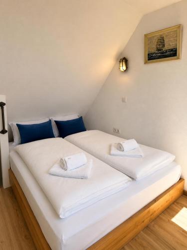 a bedroom with two beds with white sheets and blue pillows at Kajüte mit Meerblick & eigener Terrasse in Sierksdorf