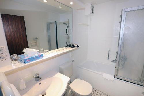 a bathroom with a sink and a toilet and a mirror at Hotel Kröger in Ennigerloh