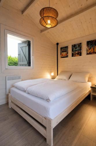 a large white bed in a room with a window at Szalona Gęś in Gąski