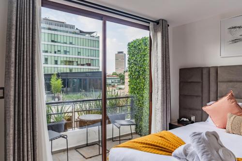 a bedroom with a bed and a balcony with a view at Casa Castillo in Mexico City