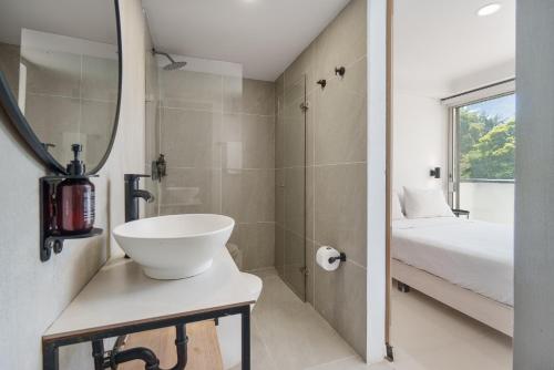 a bathroom with a sink and a shower and a bed at Hotel Santa Ana Medellin in Medellín