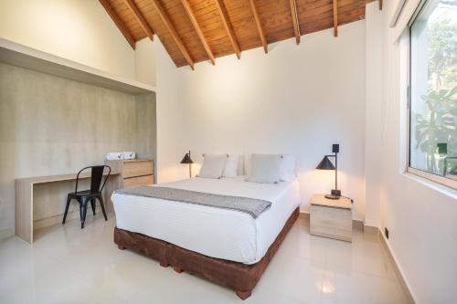 a bedroom with a bed and a desk and a window at Hotel Santa Ana Medellin in Medellín