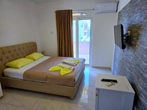 a bedroom with a bed with yellow pillows and a tv at Vila Cattleya in Donji Štoj