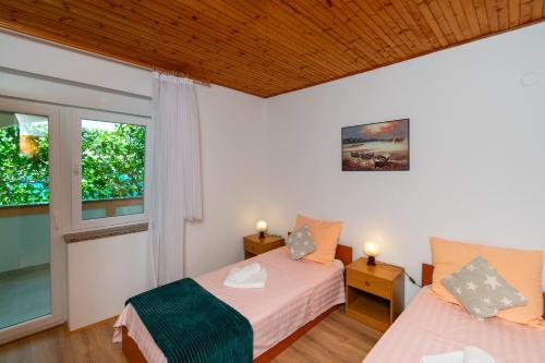 a bedroom with two beds and a window at Apartments PoolHouse in Metajna