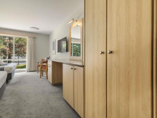 ein Zimmer mit einer Küche mit Holzschränken und einem Schlafzimmer in der Unterkunft ibis Styles Canberra in Canberra