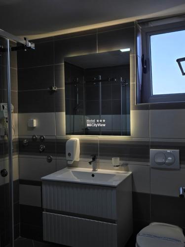 a bathroom with a sink and a large mirror at Garni Hotel Niš City View & Spa in Niš