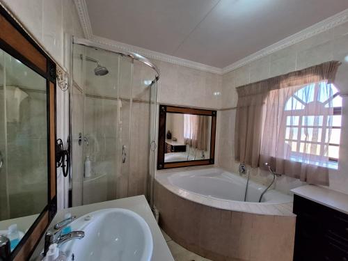 a bathroom with a bath tub and a sink at Castelo Sutil Guest House in Bloemfontein