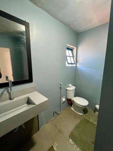 a bathroom with a toilet and a sink and a mirror at Casa Cris cabo frio in Cabo Frio