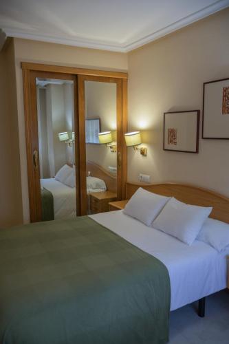 a hotel room with two beds and a mirror at Hotel La Brañina in Villablino