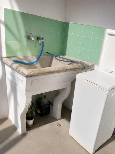 a white sink with a blue hose in a bathroom at La Casa de Pilar - Casa Completa con Cochera y Patio in San Juan