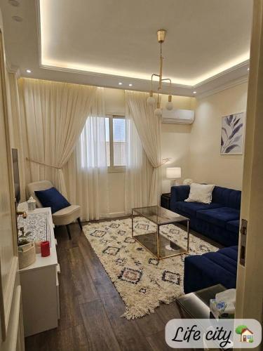 a living room with a blue couch and a glass table at Life city home in 6th Of October