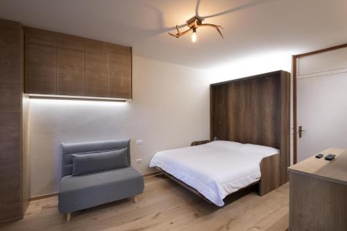 a bedroom with a bed and a chair at Bijoux Sozzine - AffittiPontediLegno in Ponte di Legno