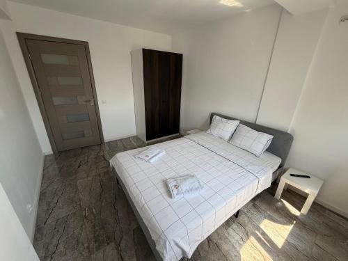 a small bedroom with a white bed and a table at EVEREST 33 Ap 3 in Bucharest