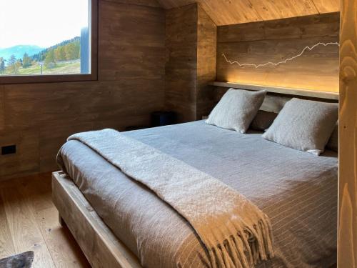 a bedroom with a bed with a wooden wall at Chalet Baita Aria - AffittiPontediLegno in Ponte di Legno