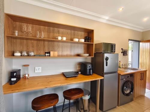 a kitchen with a counter with a refrigerator and stools at River Suite at On-the-Up in Potchefstroom
