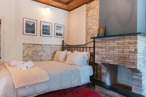 a bedroom with a bed and a brick fireplace at Κτήμα Βασίληγιάννη in Kouklésion