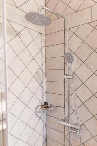 a shower in a bathroom with white tiles at Κτήμα Βασίληγιάννη in Kouklésion