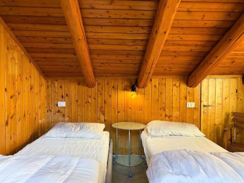 zwei Betten in einem Zimmer mit Holzwänden in der Unterkunft Panorama 3B - AffittiPontediLegno in Temù