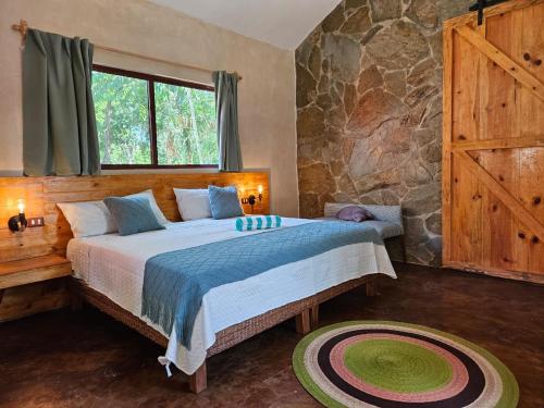 a bedroom with a bed and a stone wall at Cabañas Chechén Chaká in Leona Vicario