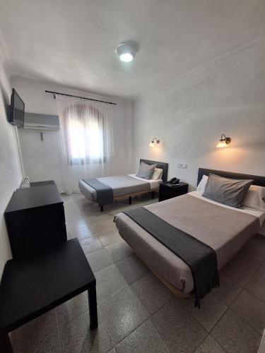 a hotel room with two beds and a chair at Hotel Portugal in Lepe