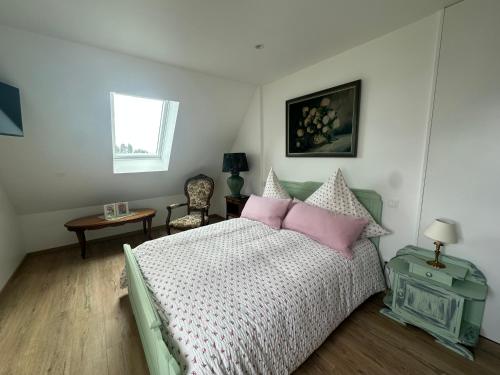 a bedroom with a bed with pink pillows and a window at Au parfum des roses in Gunstett