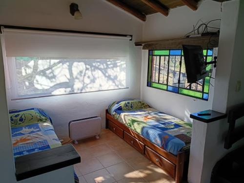 a small bedroom with two beds and a window at Casita Naranja in La Calera