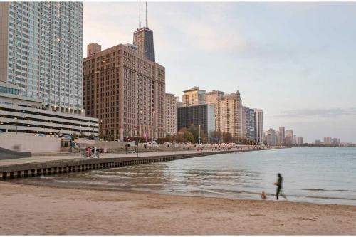 a person walking on a beach near the water with buildings at Kasa Lake Shore Chicago in Chicago