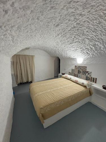 a bedroom with a bed in a white room at CUEVA RURAL PALAPA DEL PERAL in El Charcón