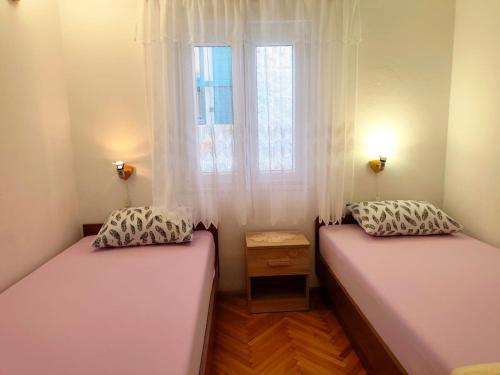 two beds in a room with a window at Apartment Josip in Primošten