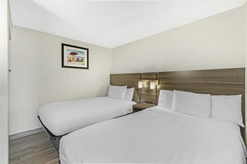 two beds in a hotel room with white sheets at SureStay Studio by Best Western Virginia Beach Oceanfront in Virginia Beach