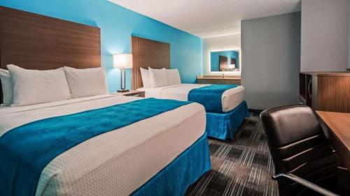 a hotel room with two beds and a desk at Quality Inn Jacksonville South in Jacksonville
