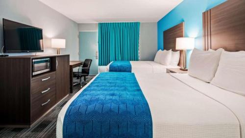 a hotel room with two beds and a desk at Quality Inn Jacksonville South in Jacksonville