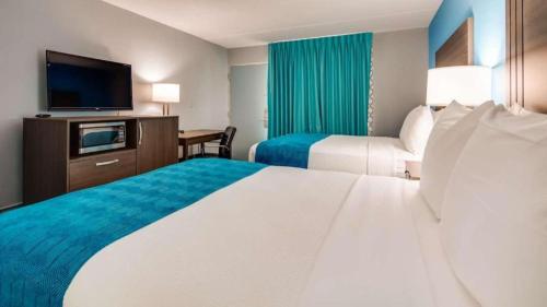 a hotel room with two beds and a flat screen tv at Quality Inn Jacksonville South in Jacksonville