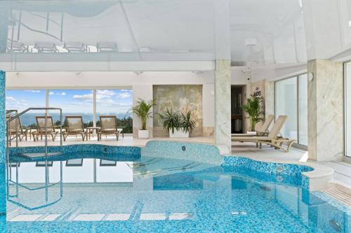 a large swimming pool in a room with a table and chairs at Maloves Resort & Spa in Władysławowo