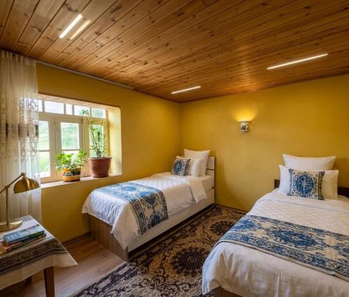 two beds in a room with yellow walls at Ecomama in Xınalıq Khinalig guest house in Xınalıq