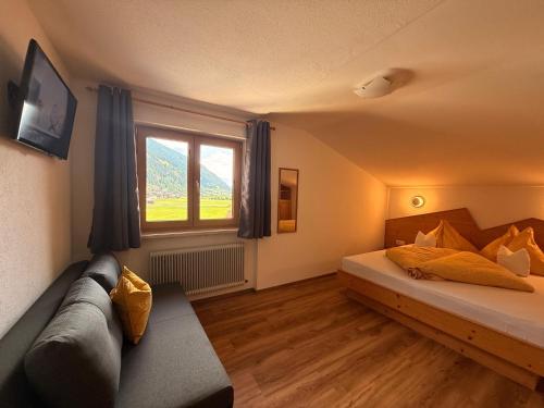 a room with a bed and a couch and a window at Alpenecho in Neustift im Stubaital