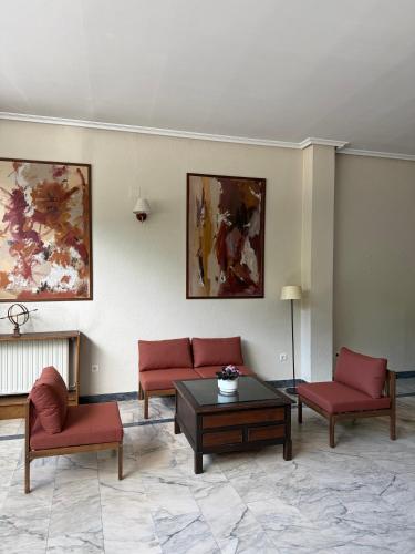 a living room with red chairs and a table at Hotel La Brañina in Villablino