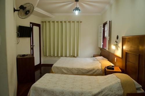 a hotel room with two beds and a window at Pousada dos Bandeirantes in Ouro Preto
