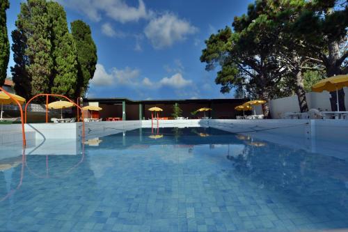 a swimming pool with umbrellas and chairs and a building at Hotel Amancay in Mar de Ajó