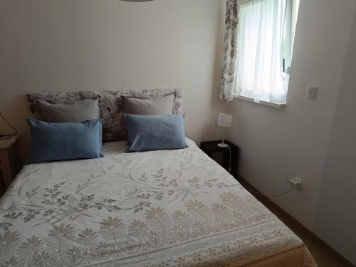 a bedroom with a bed with blue pillows and a window at La Pause in Soultz-Haut-Rhin