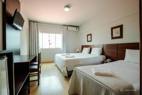 a hotel room with two beds and a television at Rede Andrade Aquarius in Porto Velho