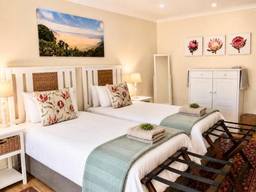 two beds in a room with two chairs at Adrenalin Addo Manor House in Addo