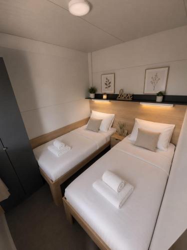 two beds in a small room with white sheets at Mobilehome Lana in Privlaka